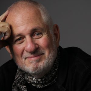 Portrait of Richard Saul Wurman looking at the camera and his hand resting against his head.